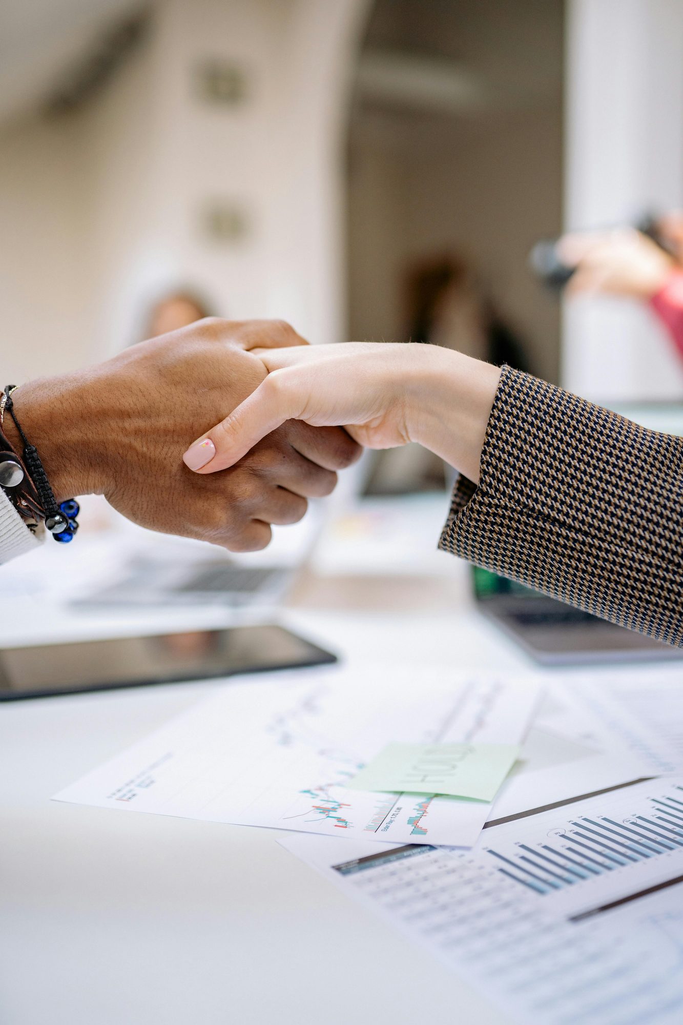 A professional handshake over research documents — the moment an engagement begins