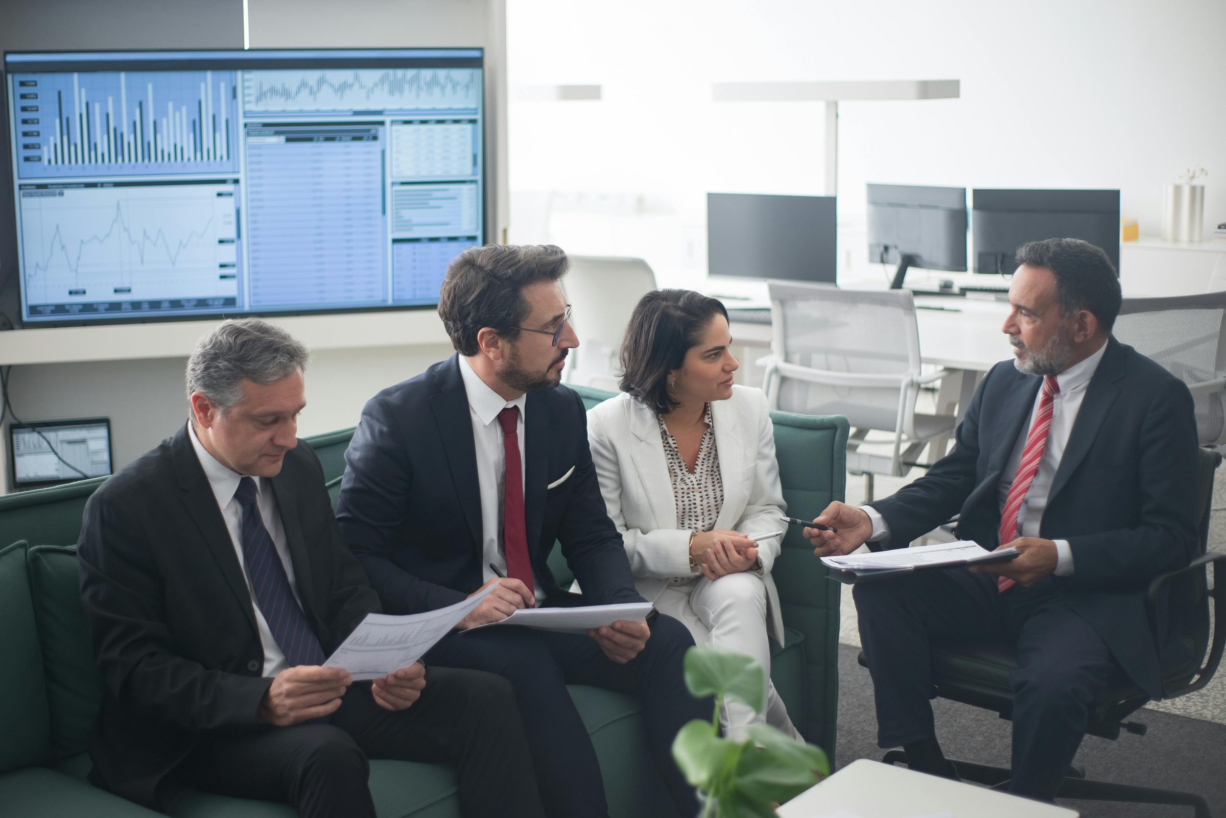 An investment committee reviewing portfolio allocations against a live market data display — the class of institutional decision-making that physical-default analysis is designed to inform